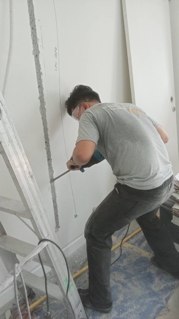 ช่างไฟกำลังกรีดผนังเพื่อติดตั้งท่อร้อยสายไฟ