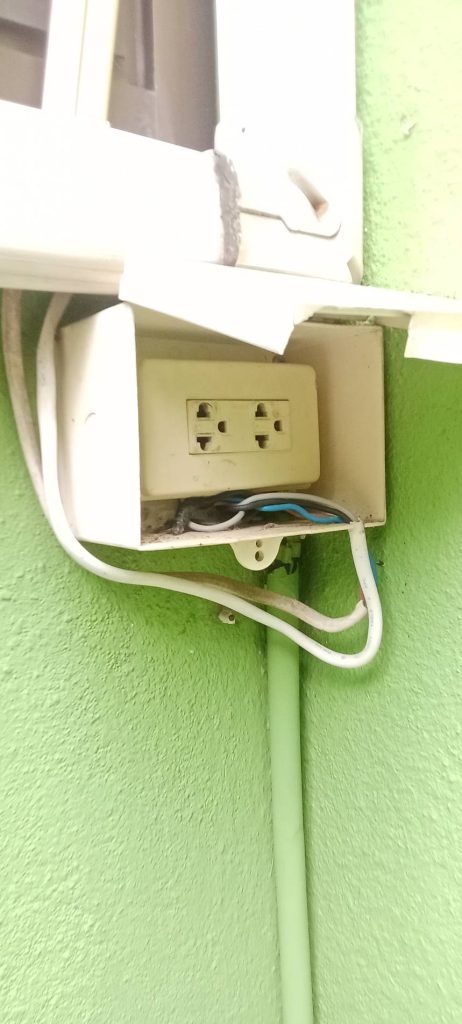 A poorly installed electrical outlet with exposed wires.
