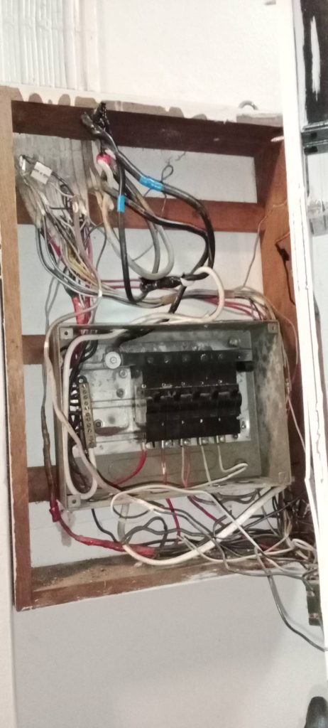 An old electrical breaker box with messy wiring