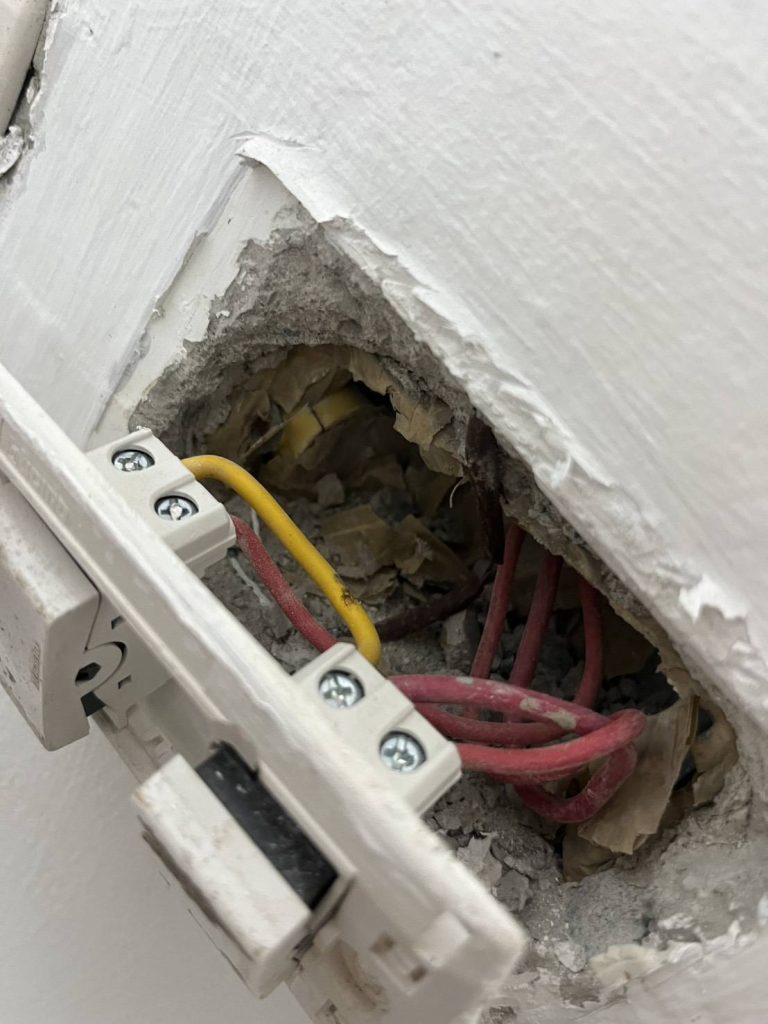 Exposed electrical wiring inside a wall switch box.