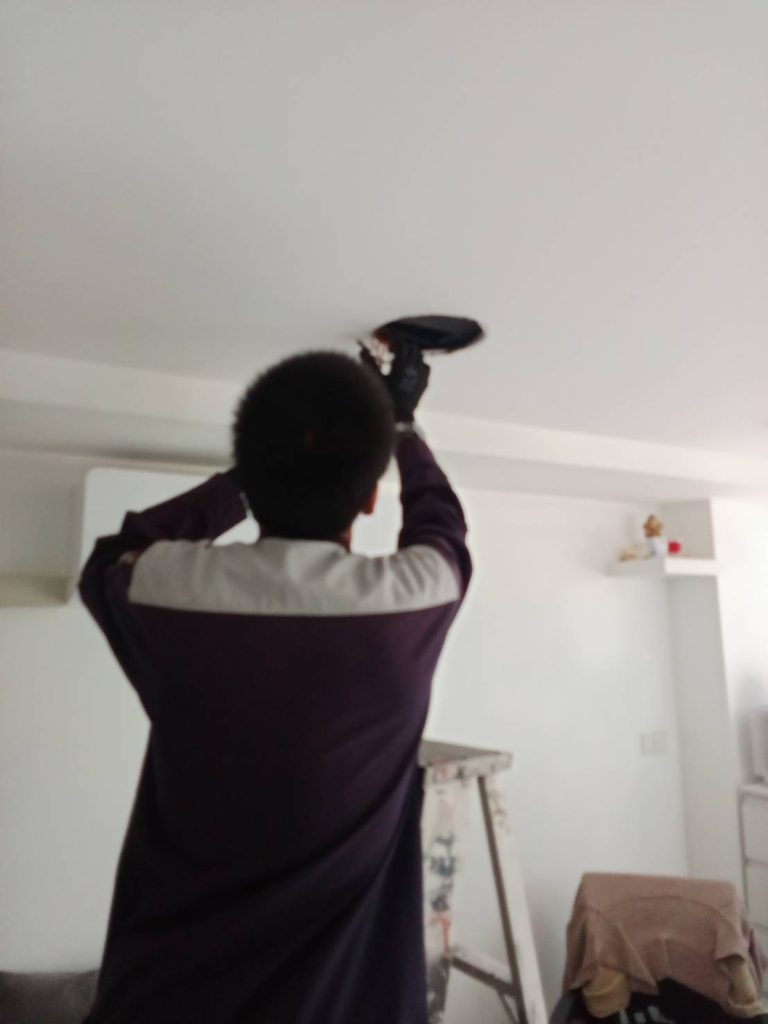 An electrician is installing a ceiling light fixture.