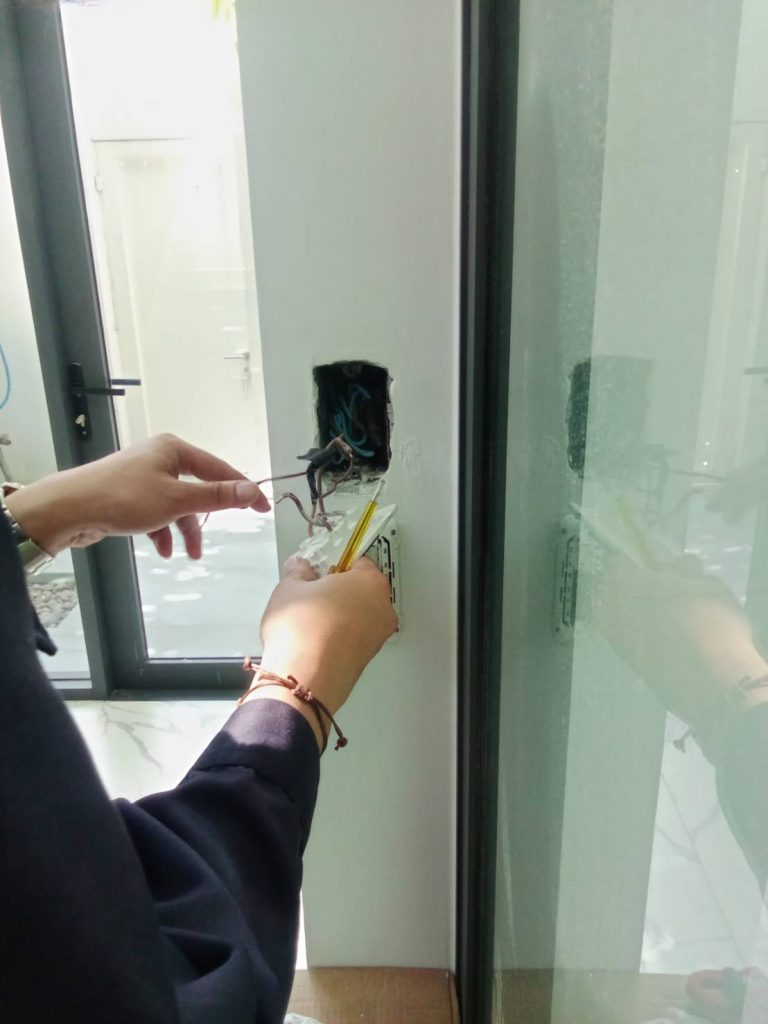 An electrician is repairing a wall switch.