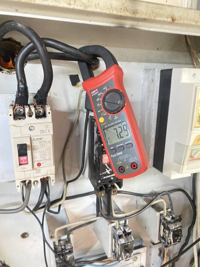 A clamp meter measures current on a main breaker circuit
