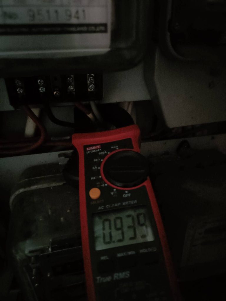 A close-up photograph shows an AC clamp meter