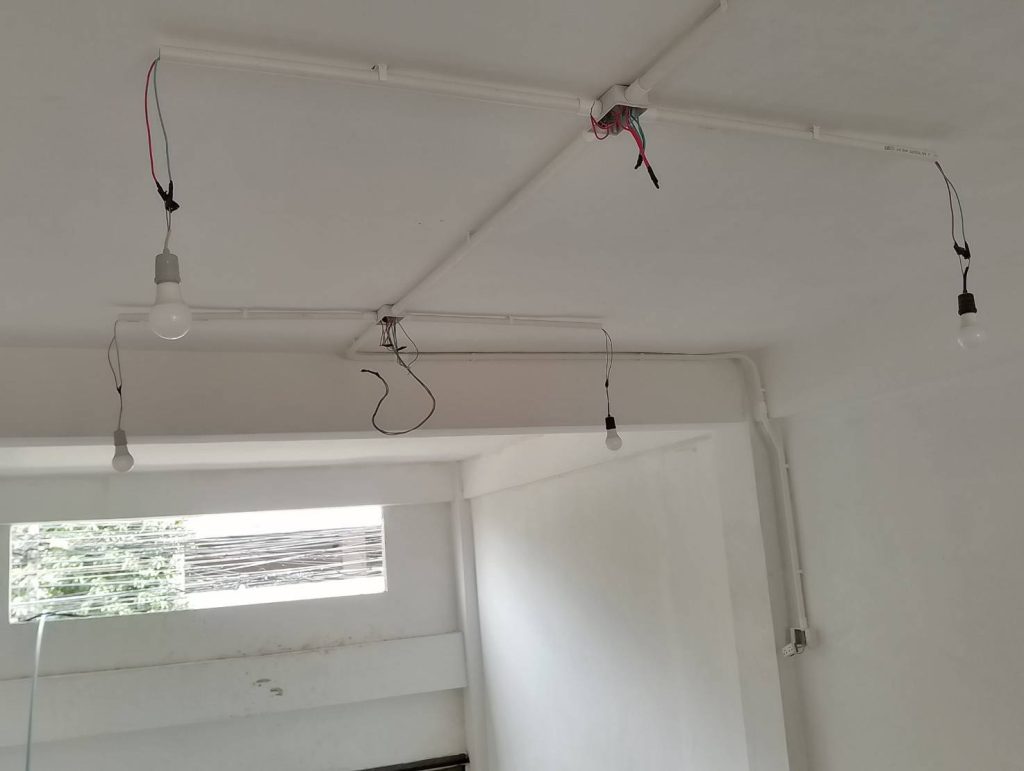 a room ceiling with exposed electrical wiring and several hanging light bulbs, suggesting unfinished