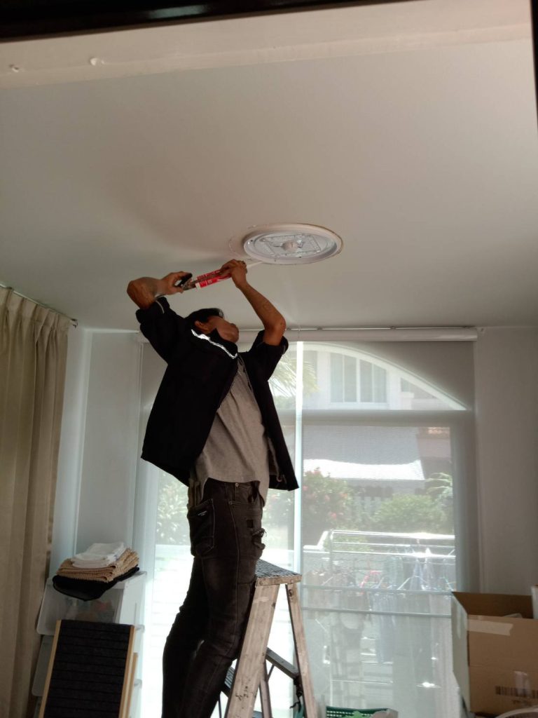 A worker is repairing a ceiling light